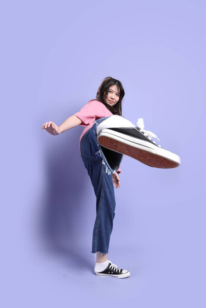 La giovane ragazza asiatica carina con vestiti casual in piedi sullo sfondo viola. - Foto, immagini