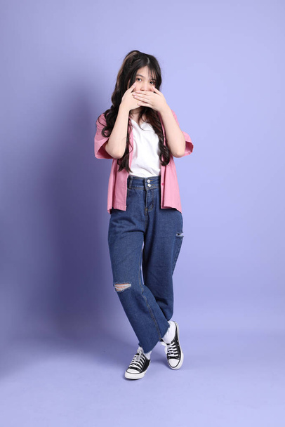 The cute young Asian girl with casual clothes standing on the purple background. - Foto, Imagem