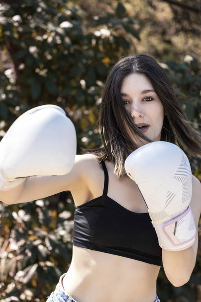 young female boxer with white gloves in a park - Fotoğraf, Görsel