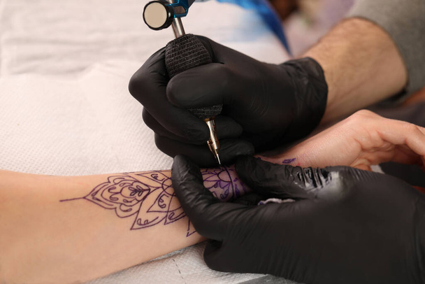 Professional artist making tattoo on hand at table, closeup - Foto, afbeelding