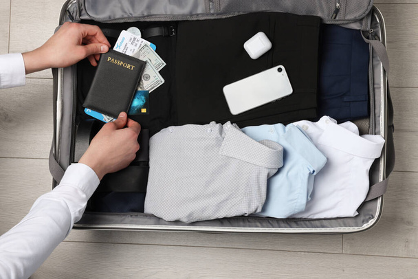 Man packing suitcase for business trip on wooden floor, top view - Fotó, kép