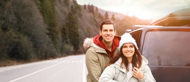 Happy couple near car on road. Banner design - Φωτογραφία, εικόνα