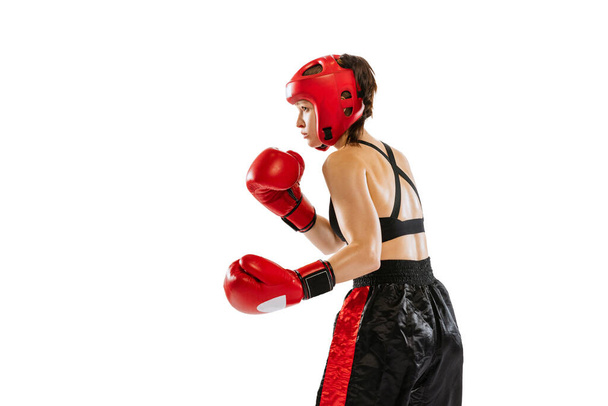 Right hook. Female boxer in boxing gloves and helmet training isolated on white background. Sport, competition, hobby, results, success concept. Sportive woman practicing in boxing. Copy space for ad - Фото, изображение