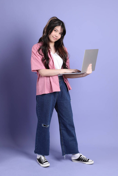 The cute young Asian girl with casual clothes standing on the purple background. - Foto, Imagen