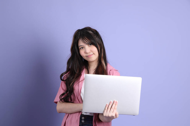 The cute young Asian girl with casual clothes standing on the purple background. - Photo, Image