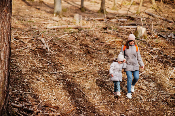 Mother with daughter wear jacket and hat in early spring forest. - Foto, immagini