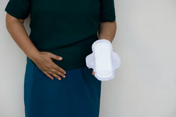 Femme tient des serviettes hygiéniques, sentir la douleur menstruelle. Concept : produit hygiénique féminin pour le jour de la période. Douleurs menstruelles le jour des règles. La santé des femmes. Hygiène intime mensuel.  - Photo, image