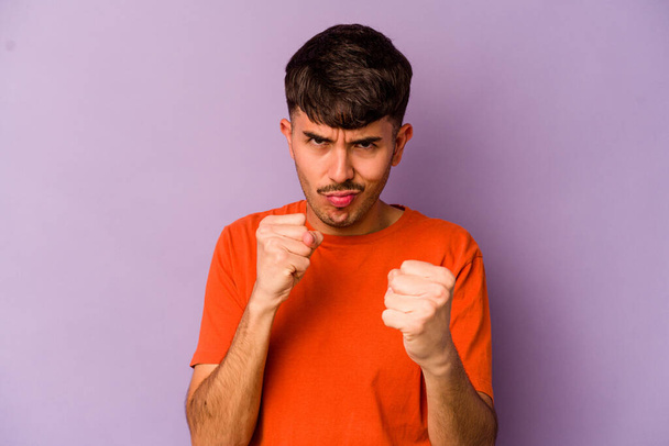 Young caucasian man isolated on purple background showing fist to camera, aggressive facial expression. - Photo, Image