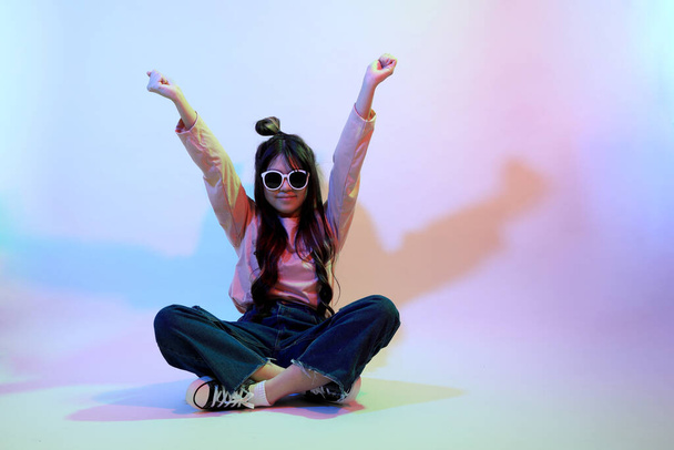 Мила азіатська дівчина з випадковим одягом, що стоїть під кольоровою блискавкою в студії.. - Фото, зображення