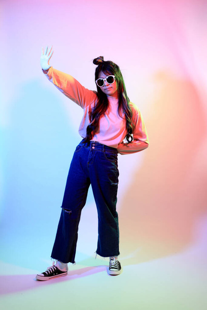 Söpö nuori aasialainen tyttö rento vaatteita poseeraa geelin väri salama studiossa. - Valokuva, kuva