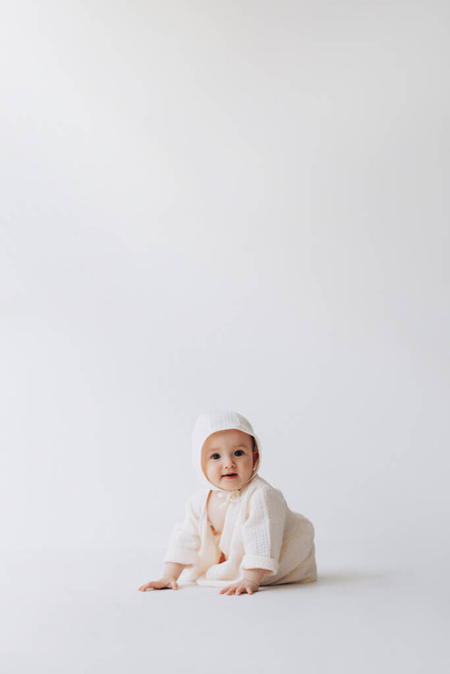 Cute studio portrait of a little newborn girl posing for a photo on a light background. A baby who has already learned to crawl and sit - Foto, afbeelding