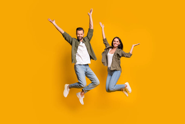 Full length photo of young girlfriend boyfriend have fun jump travel dream isolated over yellow color background. - Fotó, kép