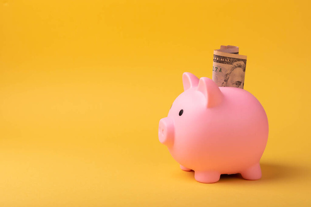 Piggy bank with dollars on a yellow background. Money saving concept. currency savings. Copyright. close-up. - Zdjęcie, obraz