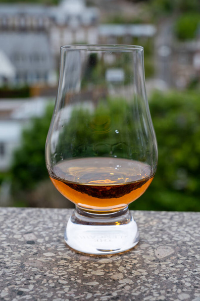 Dram of scotch whiskey with view on old houses on background, Edinburgh whisky tasting tour, Scotland - Photo, Image