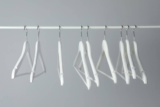 White clothes hangers on metal rail against light background - Photo, image
