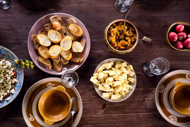 Ensalada con feta y tomates secados al sol, croutons y queso cheddar en la mesa con loza esperando a los invitados para largas conversaciones amistosas - Foto, Imagen