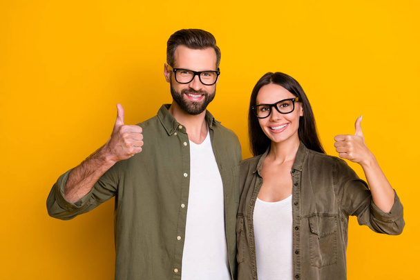 Photo of hooray millennial brunet couple thumb up wear shirts isolated on yellow background. - Foto, afbeelding