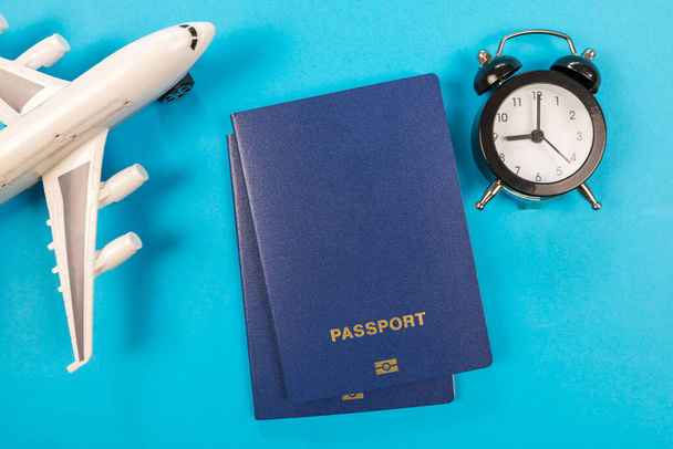 Top view ξυπνητήρι με αεροπλάνο παιχνίδι, διαβατήρια σε μπλε. Ώρα πτήσης. Η έννοια του τουρισμού και των ταξιδιών. - Φωτογραφία, εικόνα