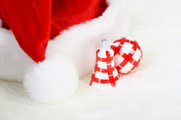 Part of Santa Claus hat with pom-pom and red and white Christmas ball and Christmas smaller bell on white fur - Foto, Imagem