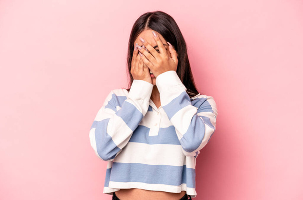 Young hispanic woman isolated on pink background blink at the camera through fingers, embarrassed covering face. - Foto, afbeelding