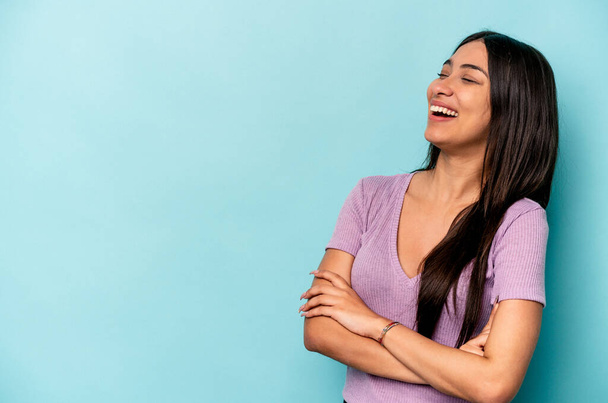 Young hispanic woman isolated on blue background smiling confident with crossed arms. - Foto, Imagen