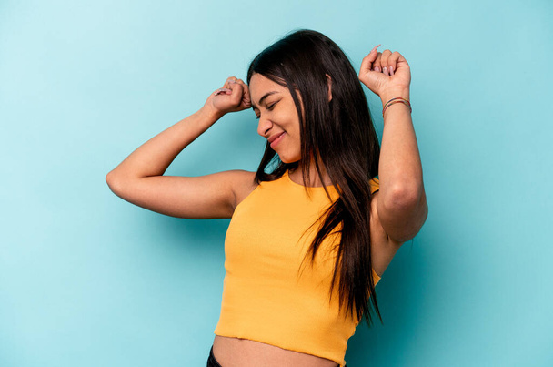 Young hispanic woman isolated on blue background celebrating a special day, jumps and raise arms with energy. - Photo, Image