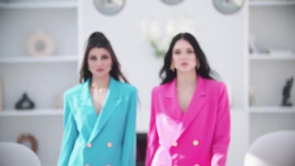 Zwei modische Frauen in rosa und blauen Blazern treten vor die Kamera. Mittelschuss - Filmmaterial, Video