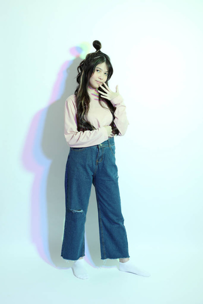La giovane ragazza asiatica carina con vestiti casual in posa sotto il colore del gel fulmine in studio. - Foto, immagini