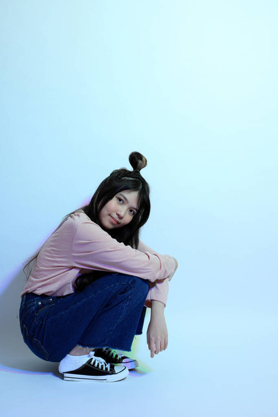 Cute młoda Azjatka dziewczyna z casual ubrania pozowanie pod kolor żelu piorun w studio. - Zdjęcie, obraz