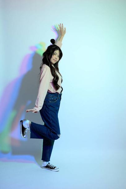 La linda chica asiática joven con ropa casual posando bajo el color del gel relámpago en el estudio. - Foto, imagen