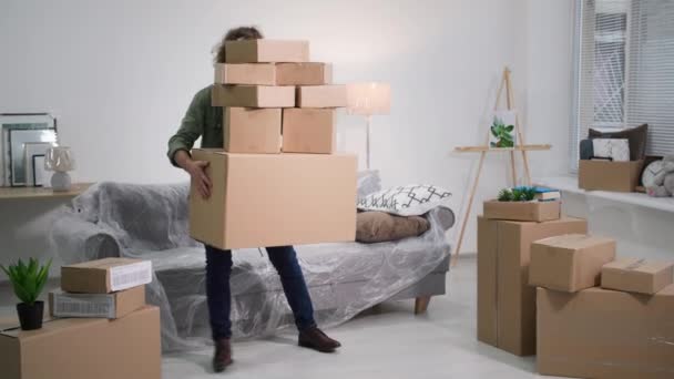 man met kartonnen dozen verliest zijn evenwicht en valt langzaam op een bank bedekt met oliedoek, problemen bij het verhuizen naar een nieuw appartement - Video