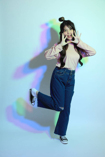 The cute young Asian girl with casual clothes posing under the gel color lightning in studio. - Photo, Image