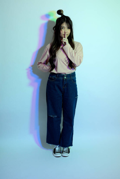 La linda chica asiática joven con ropa casual posando bajo el color del gel relámpago en el estudio. - Foto, imagen