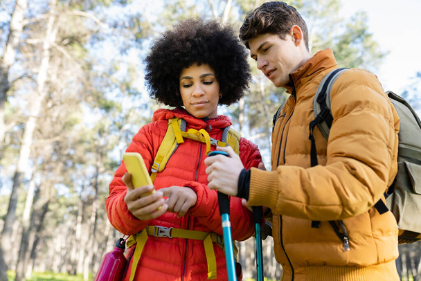 multiracial couple of backpackers, go trekking in the forest gps navigator app - Foto, Bild