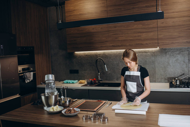 Випічка шеф-кухар кондитер молода кавказька жінка з кухонною чашею на кухонному столі. Виготовлення тортів
 - Фото, зображення