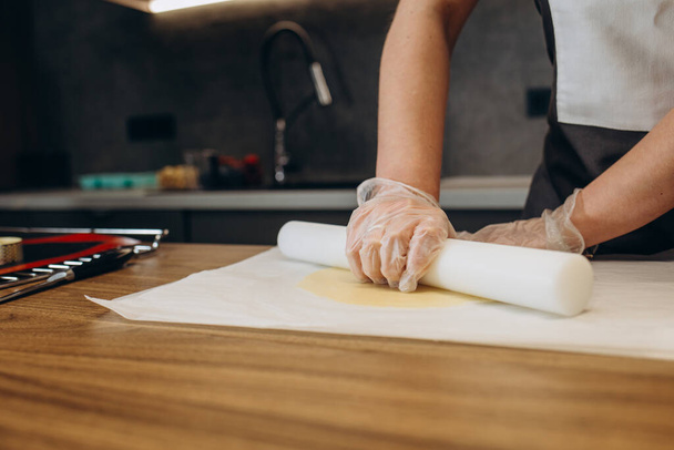 Le mani lavorano con l'impasto per fare biscotti allo zenzero freschi. Le mani delle donne fanno la pasta per biscotti fatti in casa su un tavolo di legno, cosparso di farina. Le mani delle donne stendono l'impasto - Foto, immagini