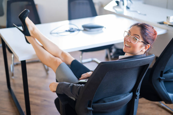 Bizneswoman siedzi ze skrzyżowanymi nogami na biurku - Zdjęcie, obraz