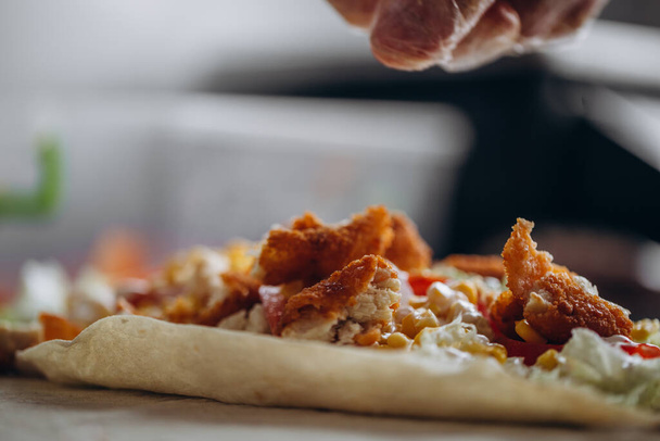 Mani da uomo avvolgendo tradizionale involucro shawarma con pollo e verdure
 - Foto, immagini