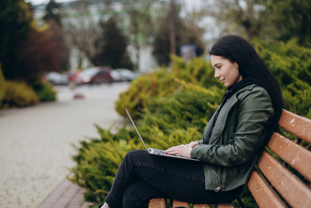 Glückliche junge Hipster-Frau arbeitet im Park am Laptop - Foto, Bild