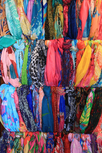 Veel kleurrijke stoffen sjaals hangen buiten een winkel - Foto, afbeelding
