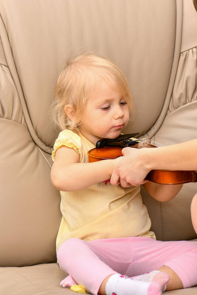 Pieni tyttö opetetaan soittamaan viulua ja autetaan pitämään instrumentti oikein.. - Valokuva, kuva