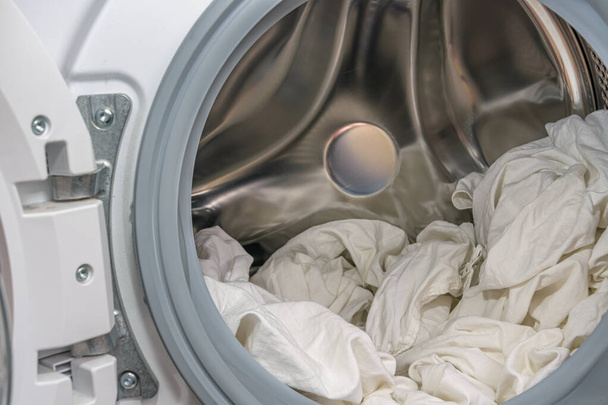 Valkoiset vaatteet avoimessa pesukoneessa. Pyykkikonsepti - Valokuva, kuva