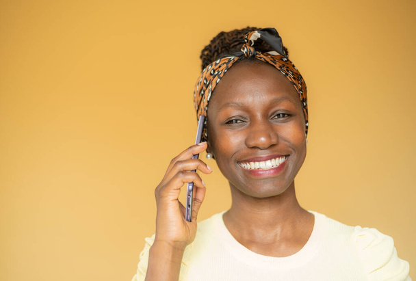 Woman speaking on the pnone while smiling against yellow background - Foto, Imagem