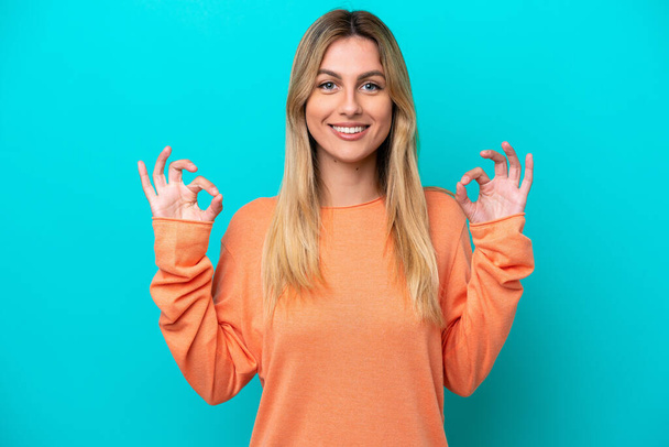 Young Uruguayan woman isolated on blue background showing ok sign with two hands - Foto, Imagen