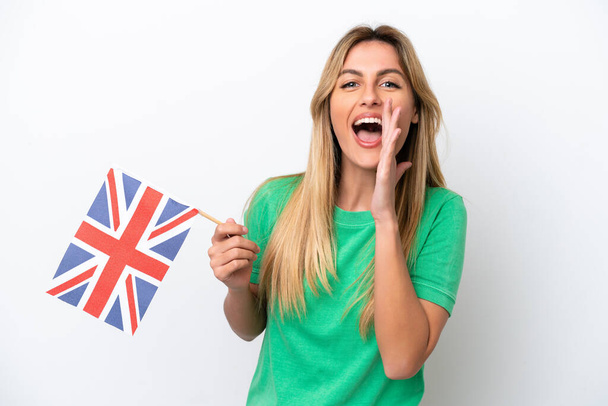 Junge uruguayische Frau mit einer britischen Flagge auf weißem Hintergrund, die mit weit geöffnetem Mund schreit - Foto, Bild