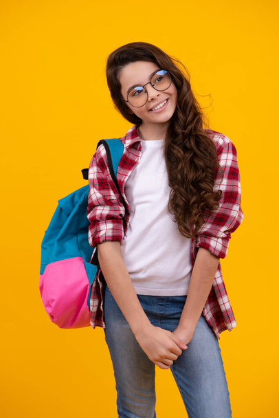 Školačka ve školní uniformě s batohem. Dospívající dívka student na žlutém izolovaném pozadí. Učení a vzdělávání dětí. Šťastný teenager, pozitivní a usměvavé emoce školačky - Fotografie, Obrázek