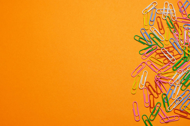 Colored paper clips on a orange background - Fotografie, Obrázek