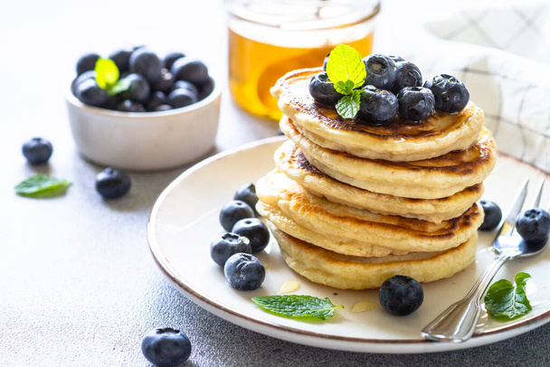 Pancakes stack with fresh blueberries and honey close up. - Photo, Image