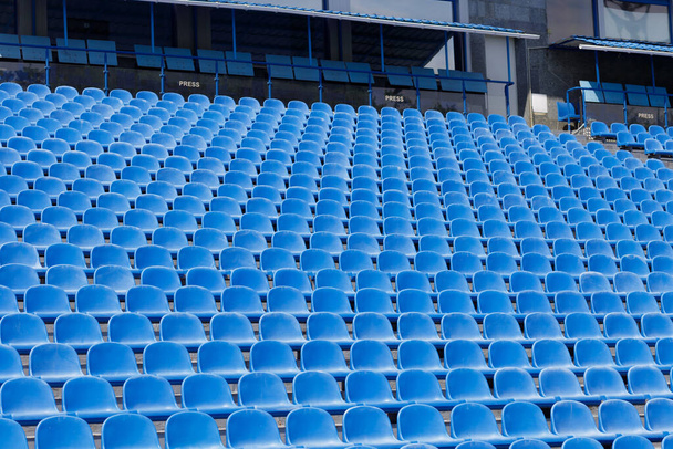  Asientos de plástico azul en la tribuna abierta del estadio deportivo. Un lugar para la prensa. Foto de alta calidad - Foto, imagen