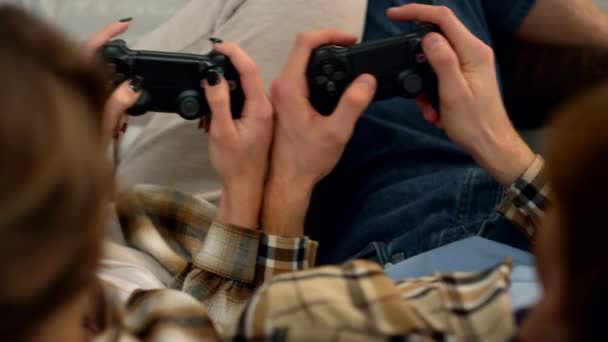 Néhány kéz joystickot használ otthon. Az emberek jól érzik magukat videojátékkal. Ismeretlen férfi barátok lökdösik egymást, élvezik a játékversenyt. Izgatott játékosok pihenő konzol. - Felvétel, videó
